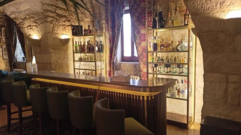 Timber bar counter and backlit bottle shelving in a stone vault