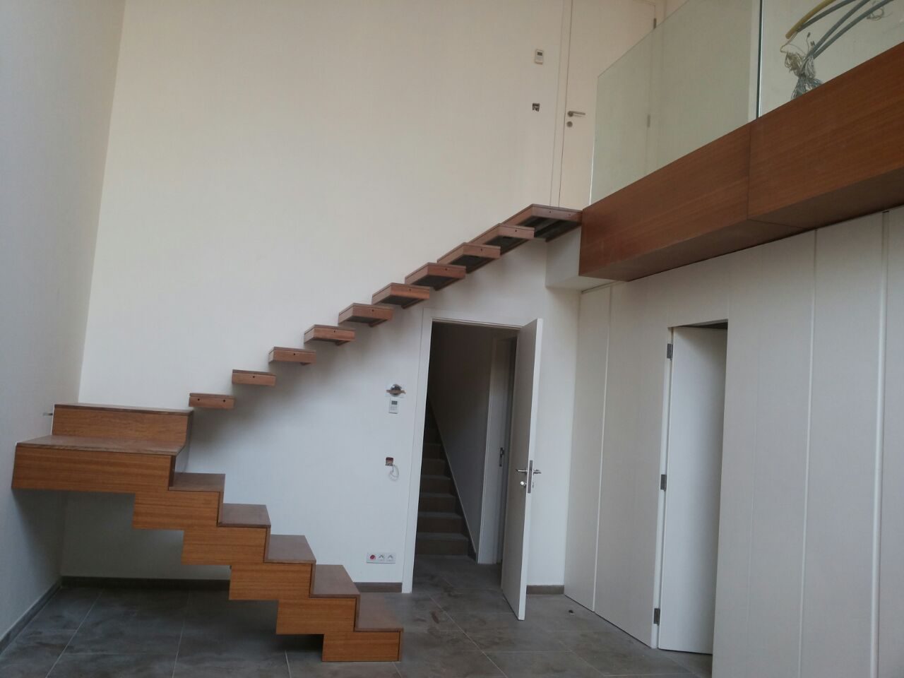 Cantilevered timber staircase against a white wall