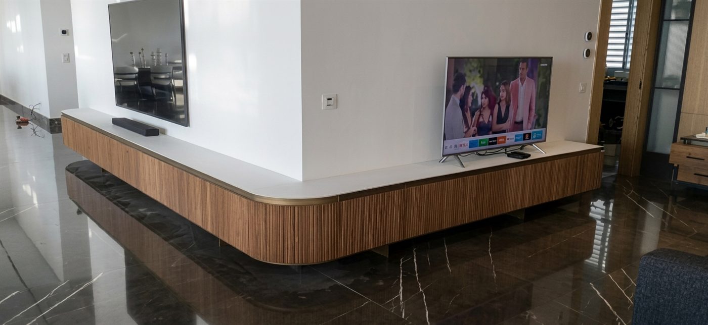 Curved fluted timber TV cabinet on a marble floor