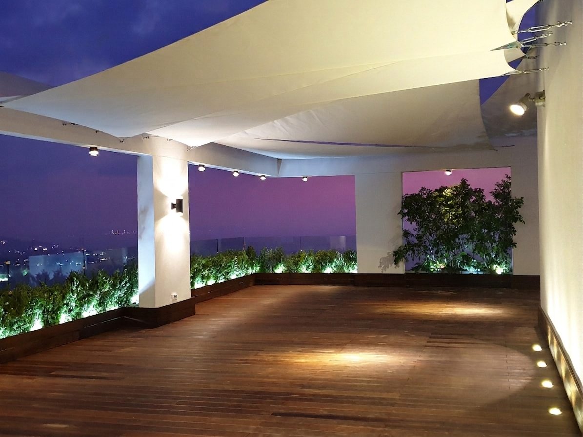 Hardwood deck under shade sails at dusk, city lights beyond