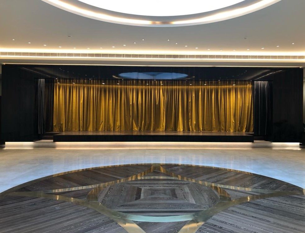 Stage with a gold curtain, timber apron and stone medallion floor
