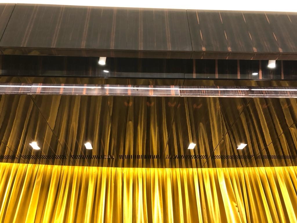 Gold stage curtain seen from below with the lighting bar above