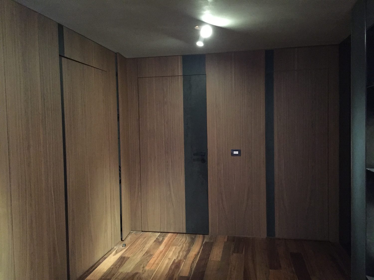 Entrance corridor lined in timber panelling with a concealed door