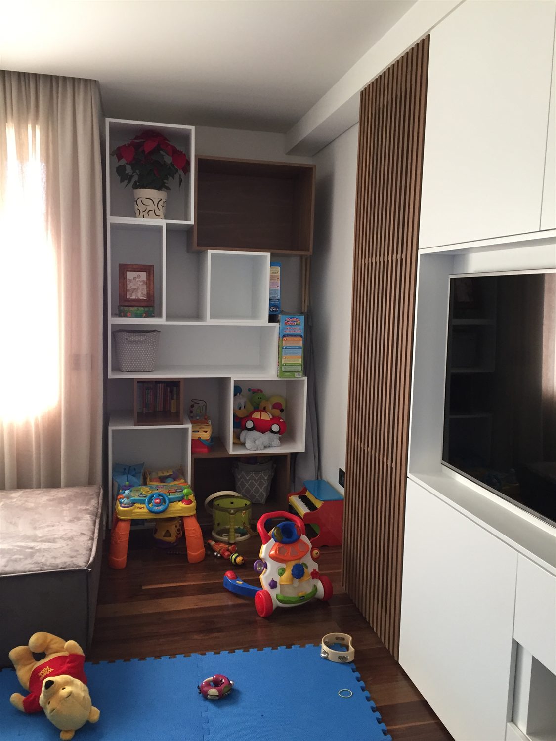 Children's playroom with modular wall shelving and a slatted screen