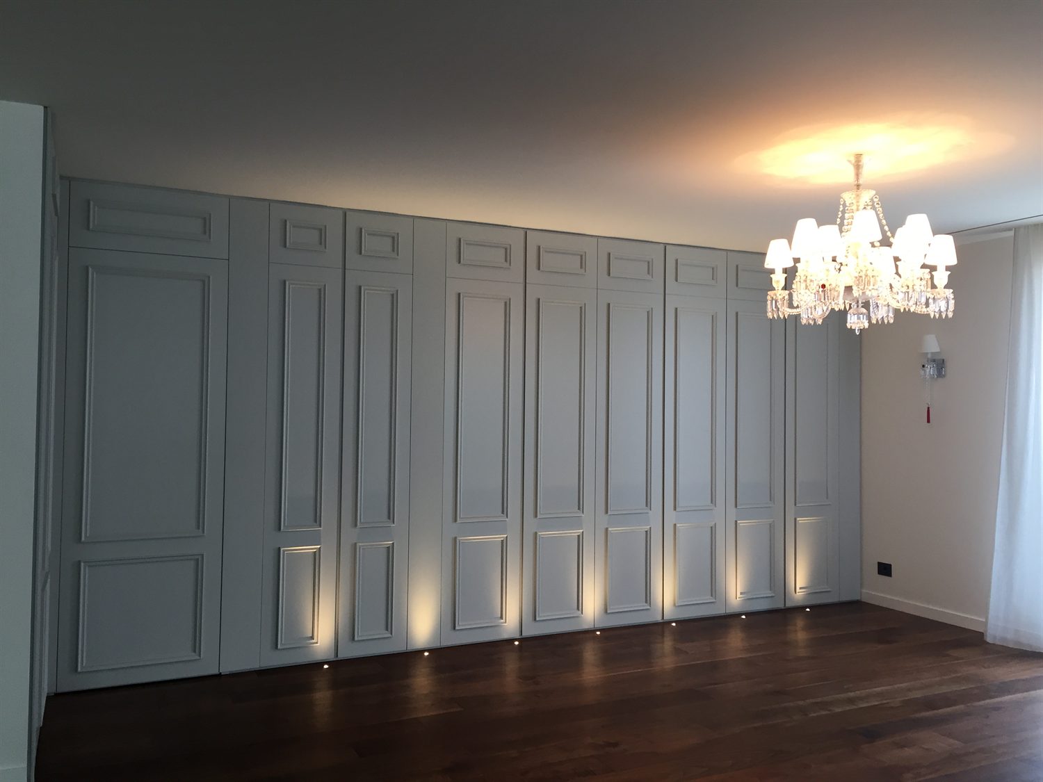 Dressing room with panelled wardrobe doors and a chandelier