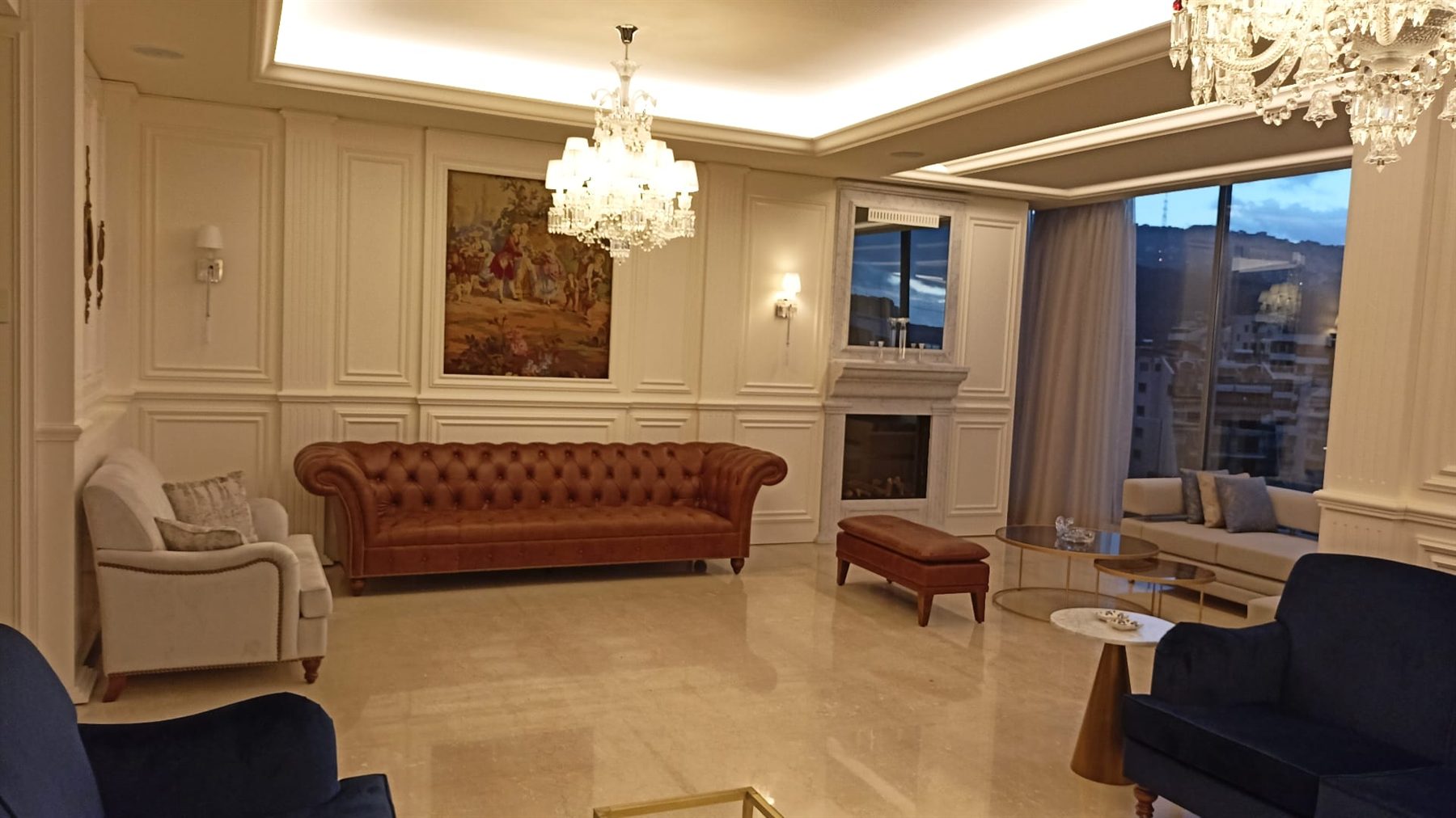 Main salon with panelled walls, chandeliers and a leather chesterfield