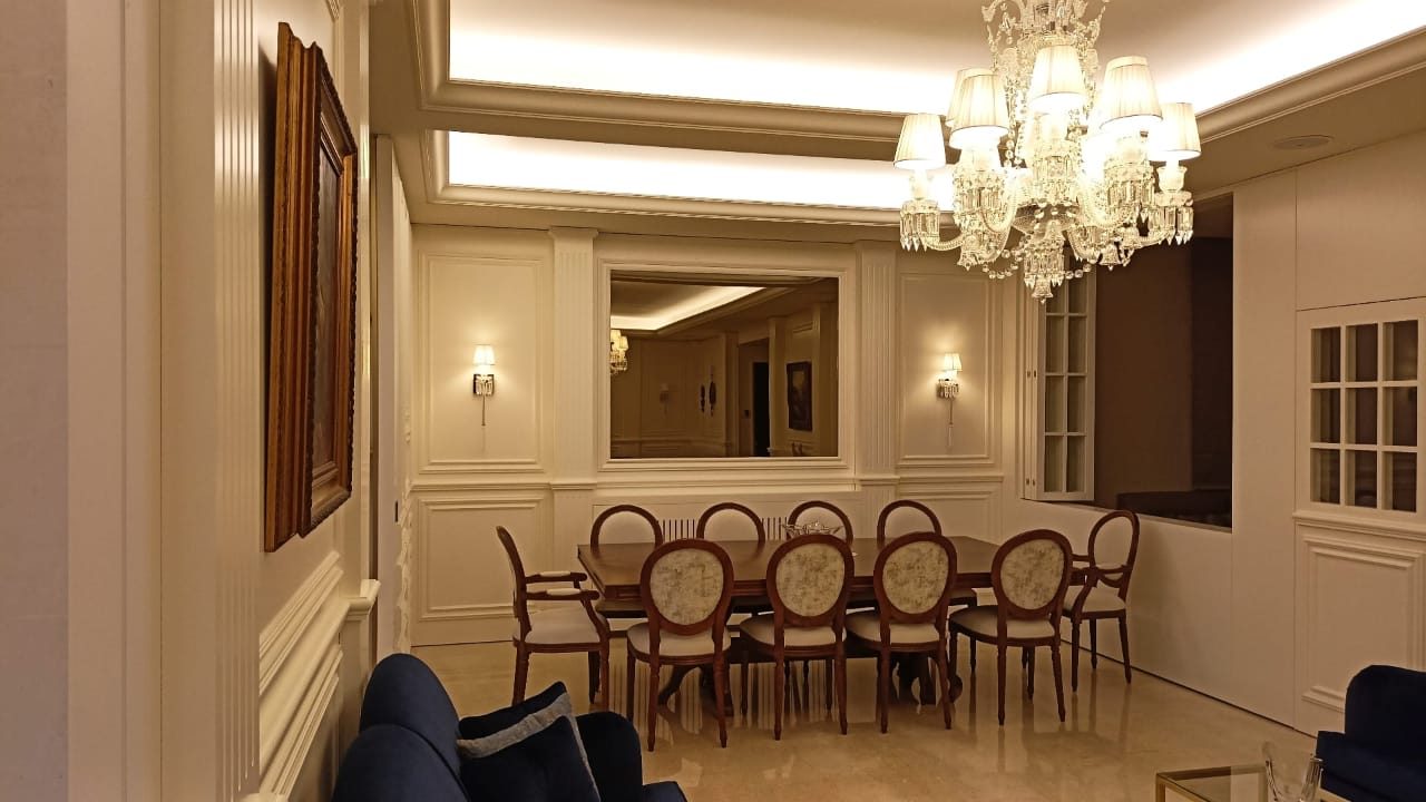Dining room seen past a chandelier and wall panelling
