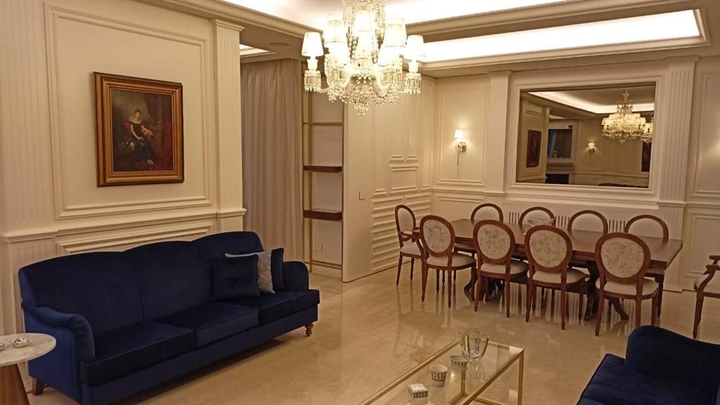 Sitting room with a blue velvet sofa and the dining room beyond
