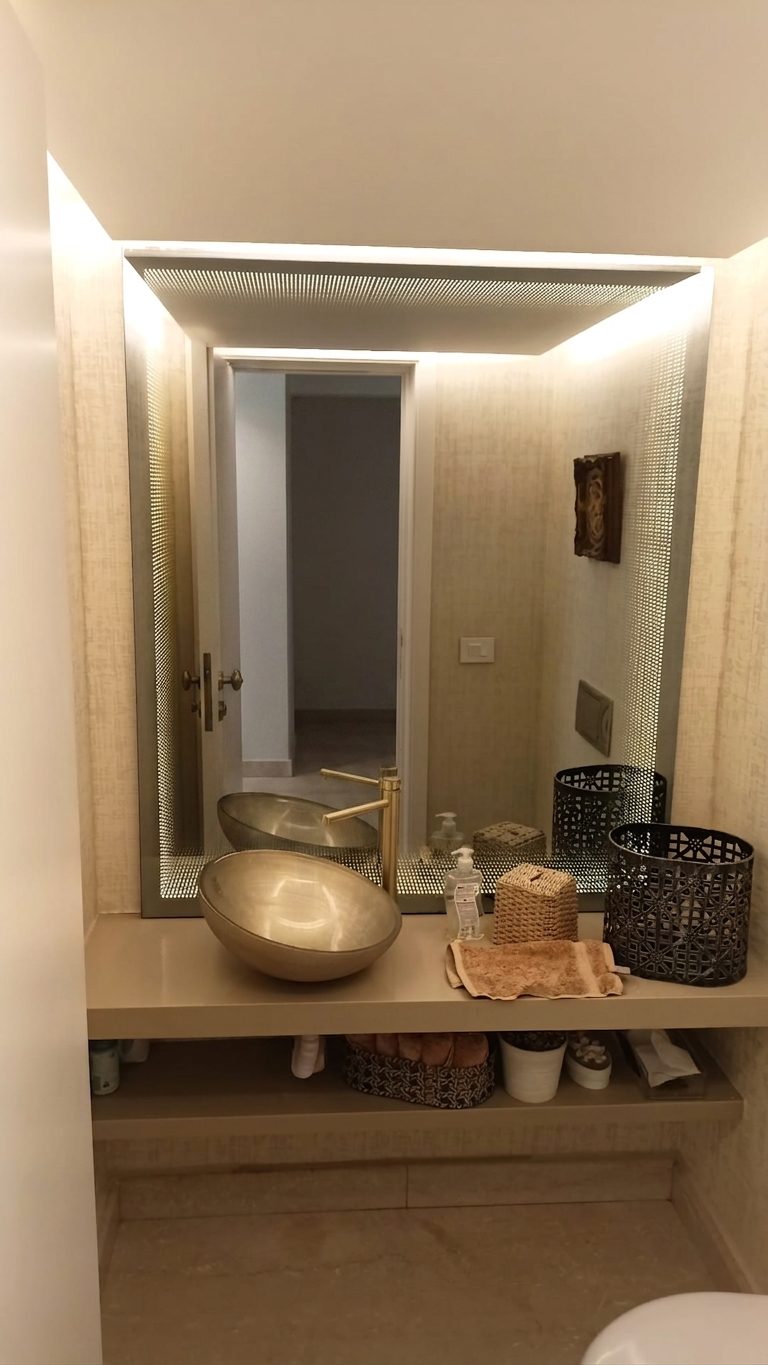 Powder room with a backlit mirror and a marble shelf