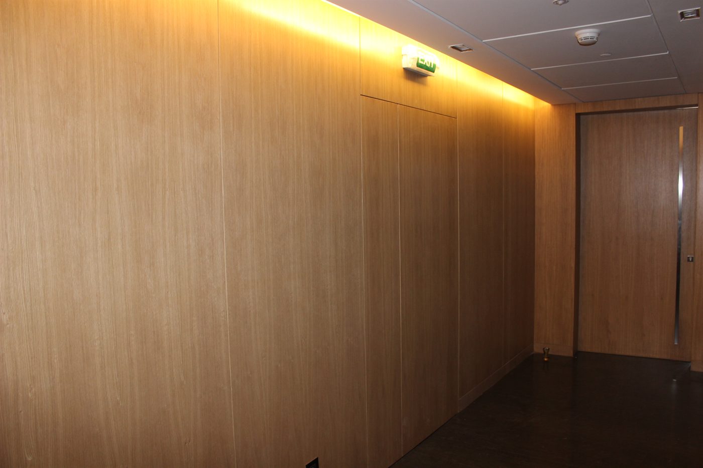 A corridor lined in full-height timber wall panelling with a concealed door